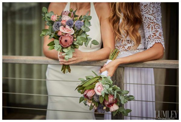 A bride and her bridesmaid are standing next to each other holding bouquets of flowers.