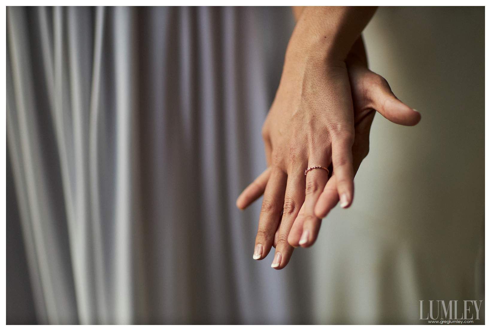 A bride and groom are holding hands with their wedding rings on their fingers.