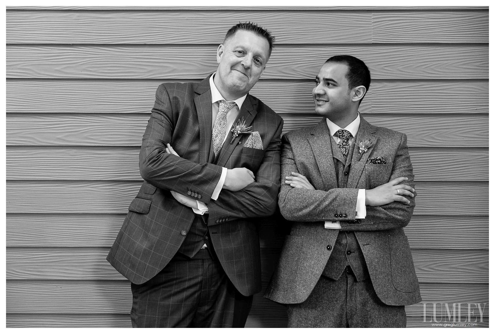 Two men in suits are standing next to each other with their arms crossed.