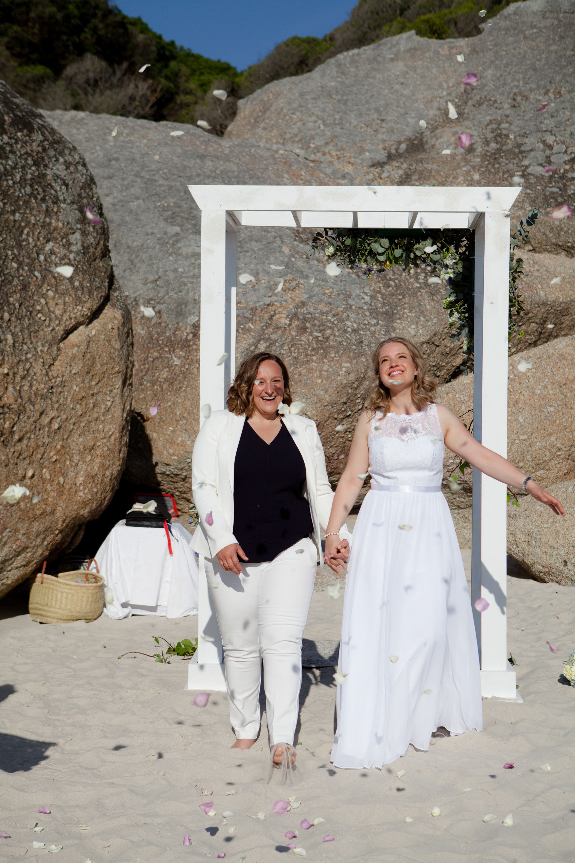 Two women are standing next to each other on a beach holding hands.