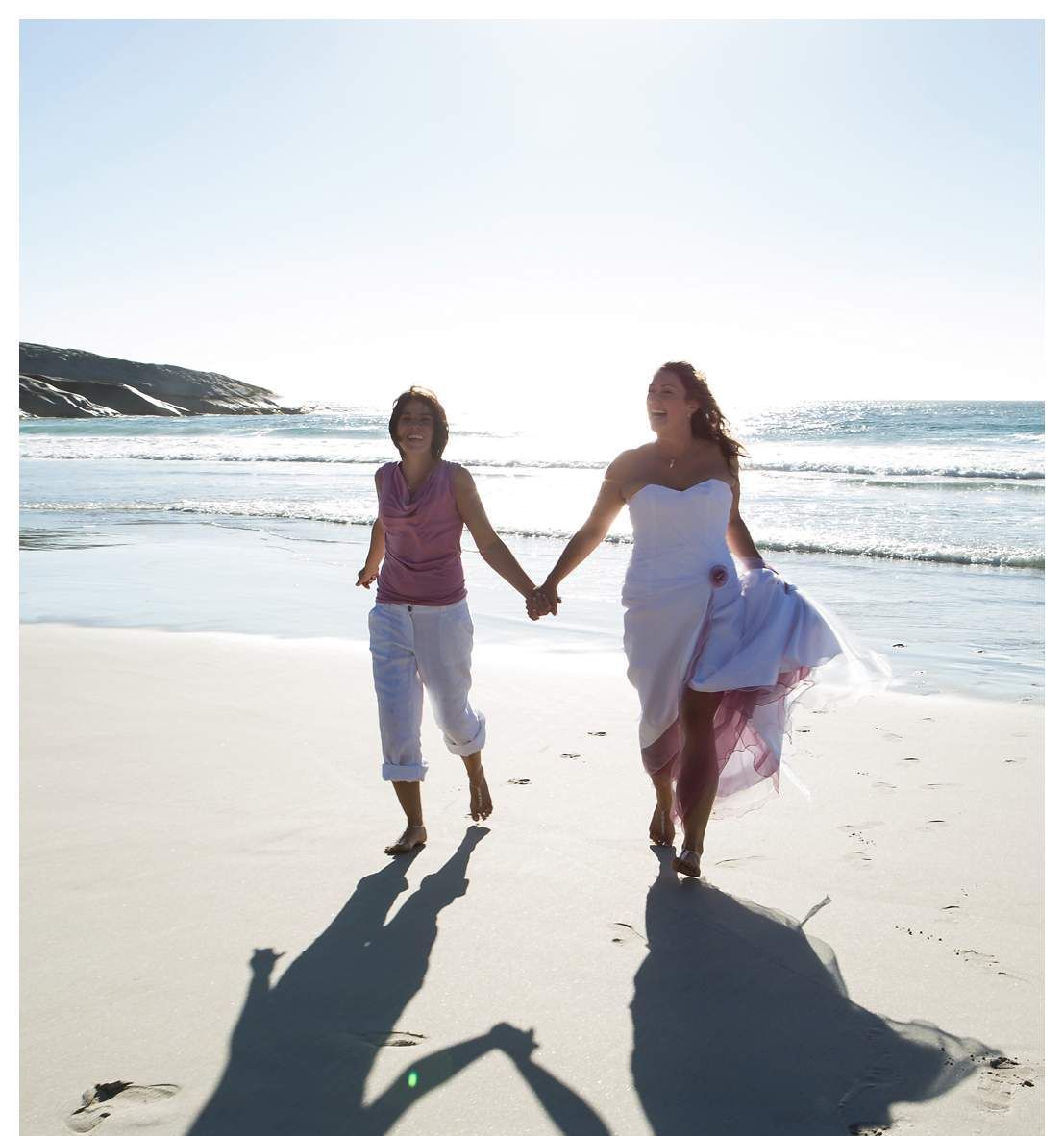 Two women are walking on the beach holding hands