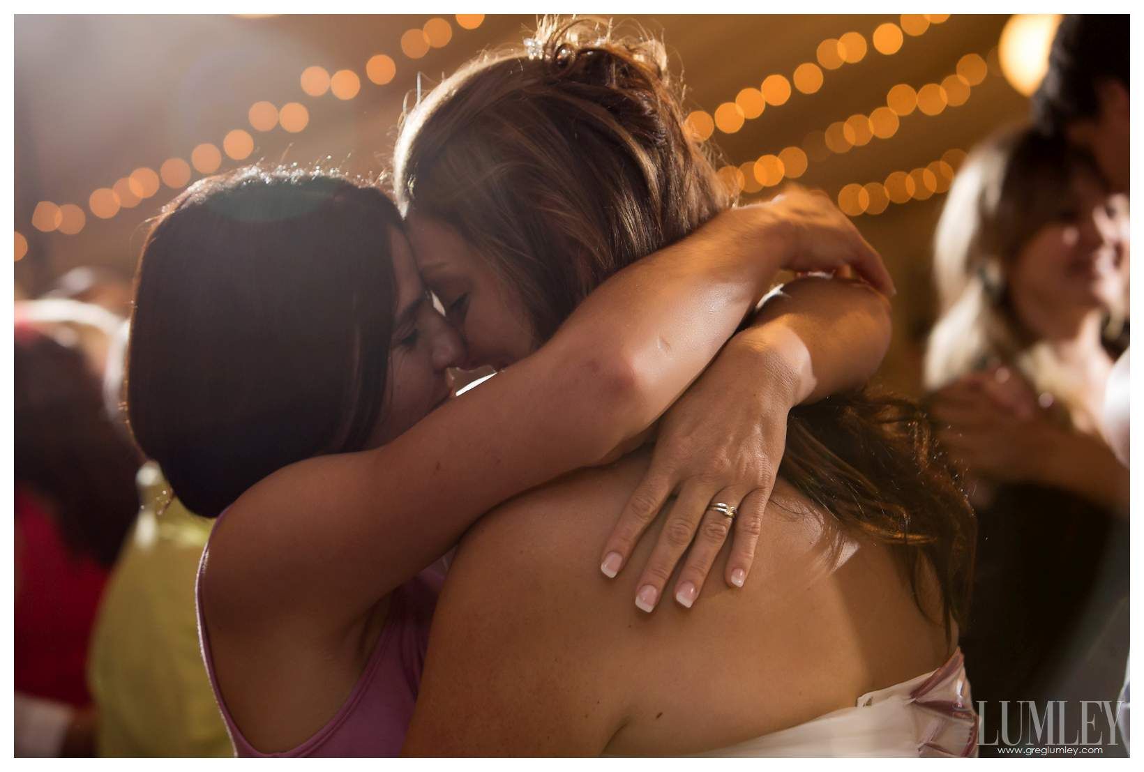 Two women are hugging each other at a wedding reception.