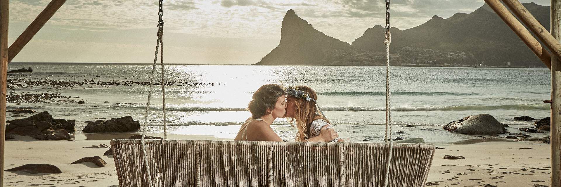 A bride and groom are standing on a beach near the ocean.