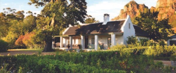 A large white house is surrounded by trees and bushes.