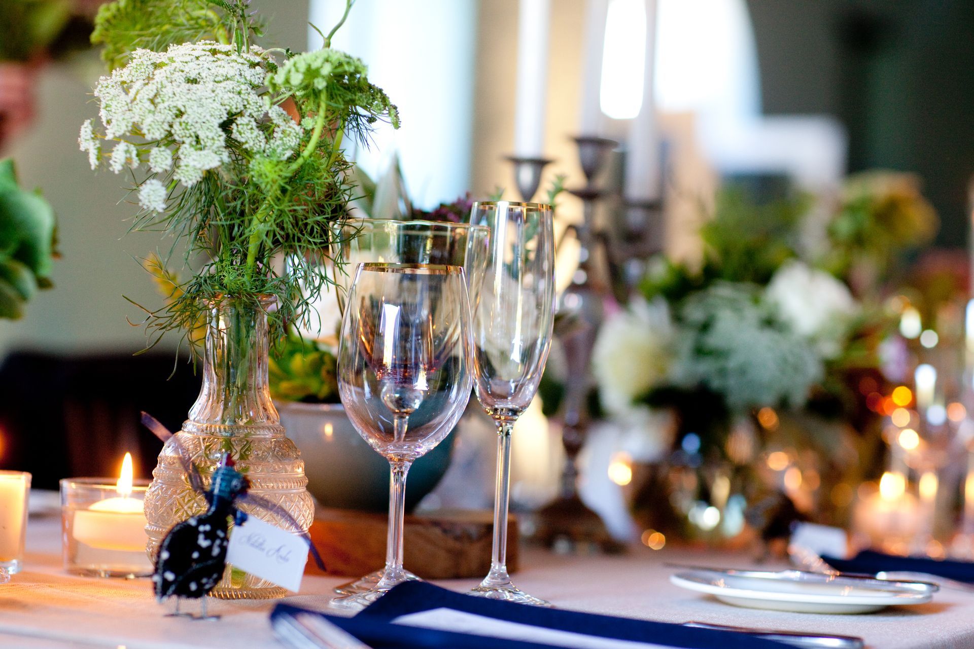 A table with a vase of flowers and wine glasses on it.