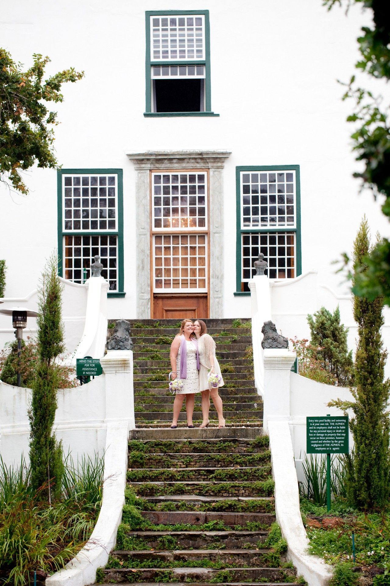 Two women are standing on a set of stairs in front of a white building.
