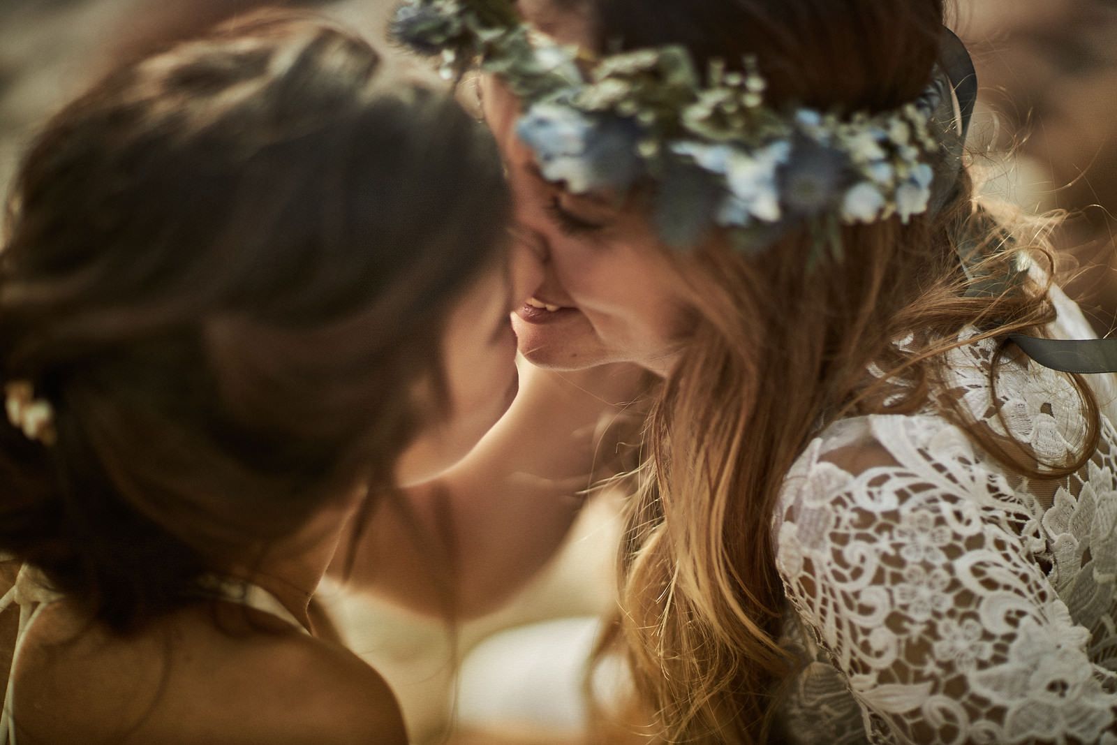 A bride and groom are kissing on a rocky beach.