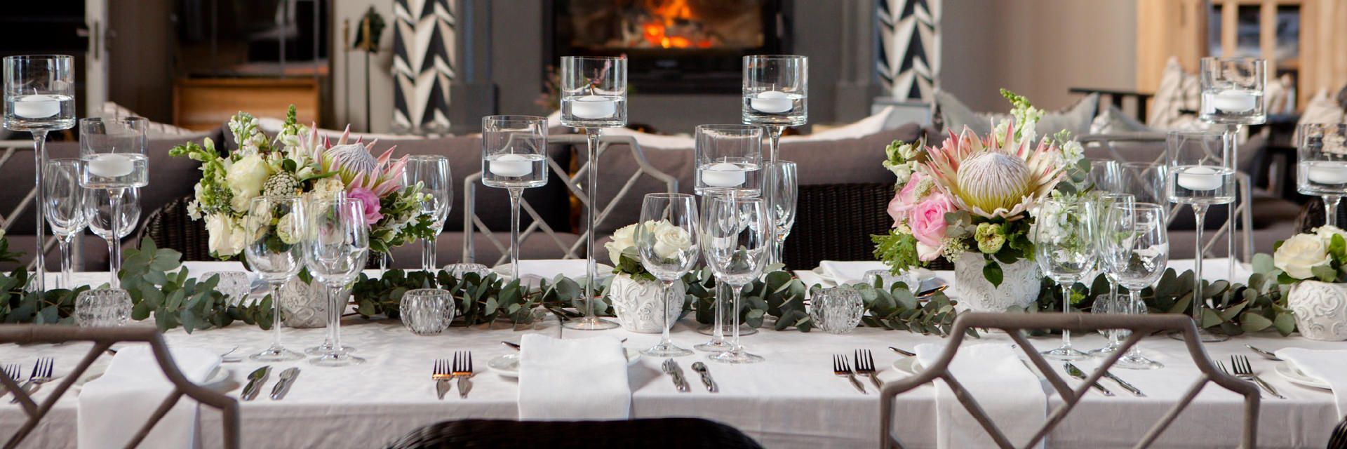 A long table set for a wedding reception with flowers and glasses.