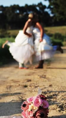 A blurry picture of a bride and groom with a bouquet of pink flowers in the foreground