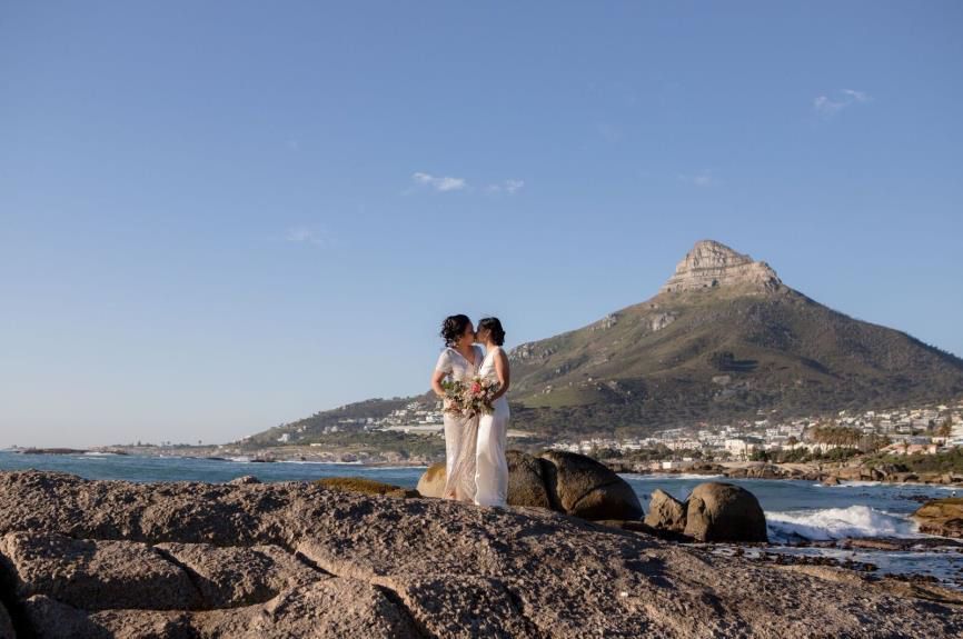 A couple of women standing on top of a rocky cliff overlooking the ocean.