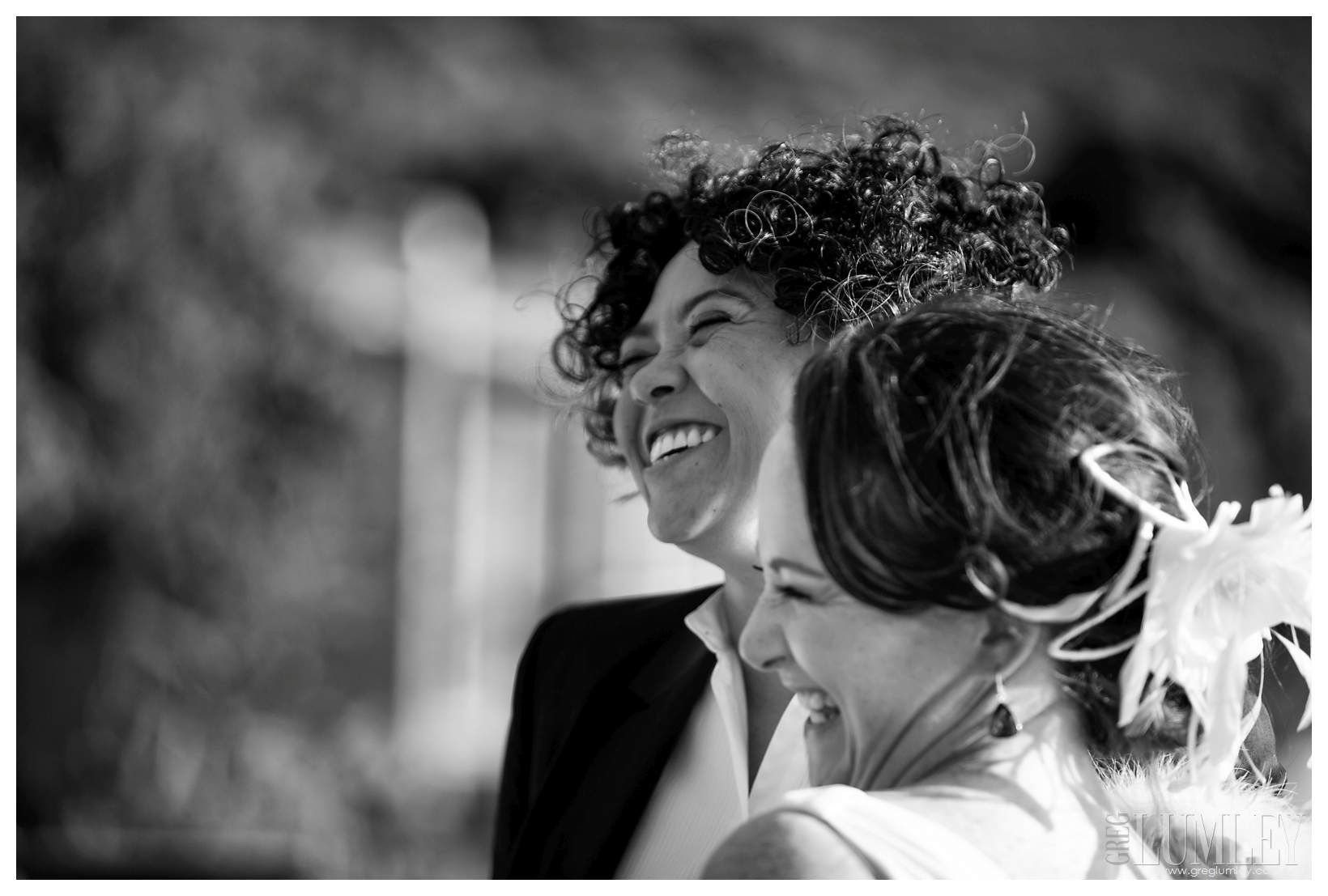Two women are laughing together in a black and white photo.
