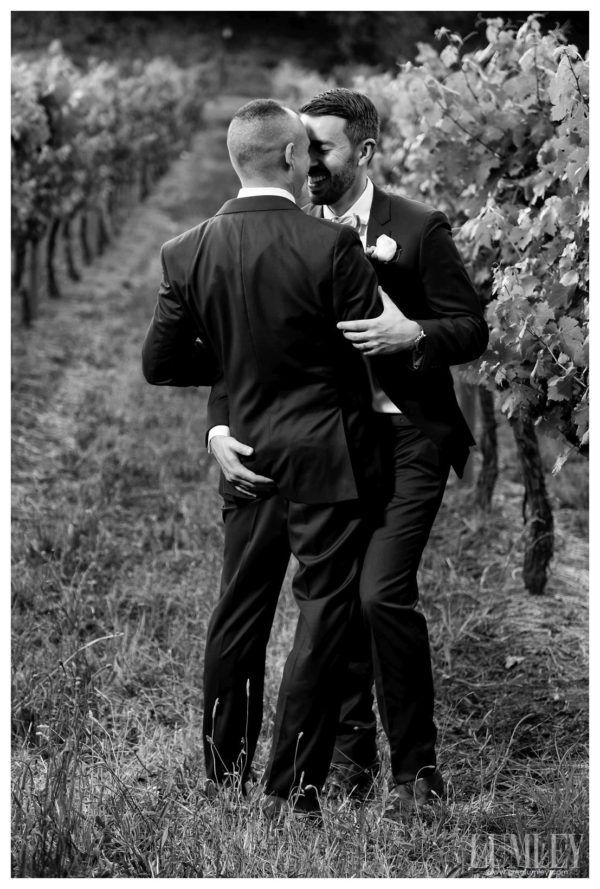 Two men in suits are hugging each other in a field.