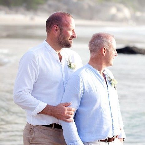 A bride and groom are holding hands in front of mountains