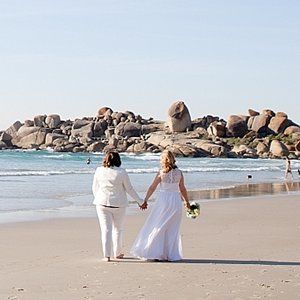 A bride and groom kissing at their wedding ceremony in front of a crowd of people.