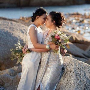 A bride and groom are posing for a picture with their wedding party in a field.