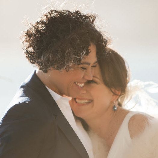 A man in a suit and tie is standing next to a woman in a wedding dress.
