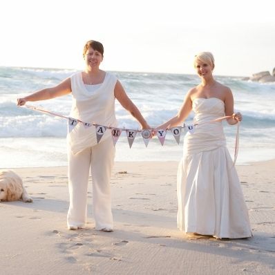 A bride and groom are posing for a picture on the beach.