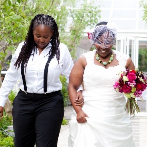 A bride and groom are kissing in a field of purple flowers.