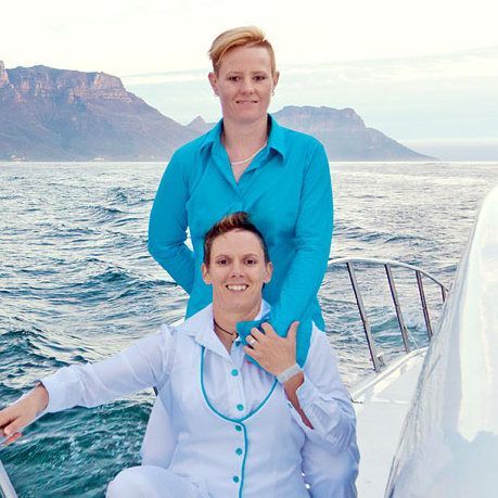 A bride and groom are holding hands in front of mountains