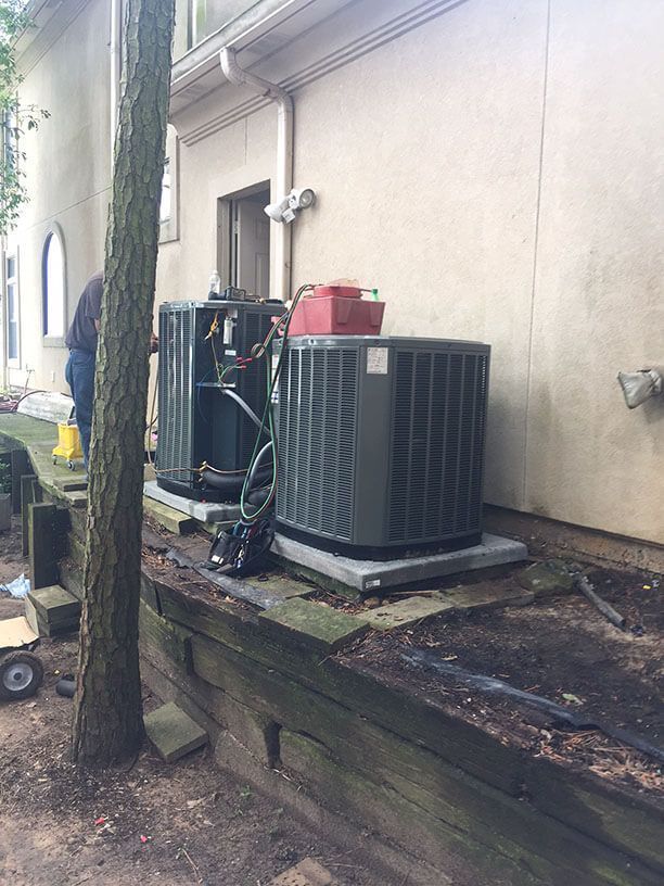 Two air conditioners are sitting on the side of a house.