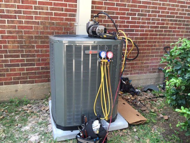 A large air conditioner is sitting outside of a brick building.