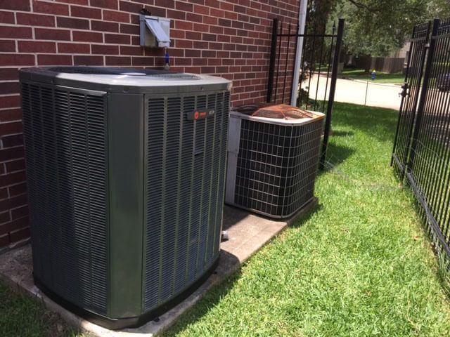 Two air conditioners are sitting on the side of a brick building.