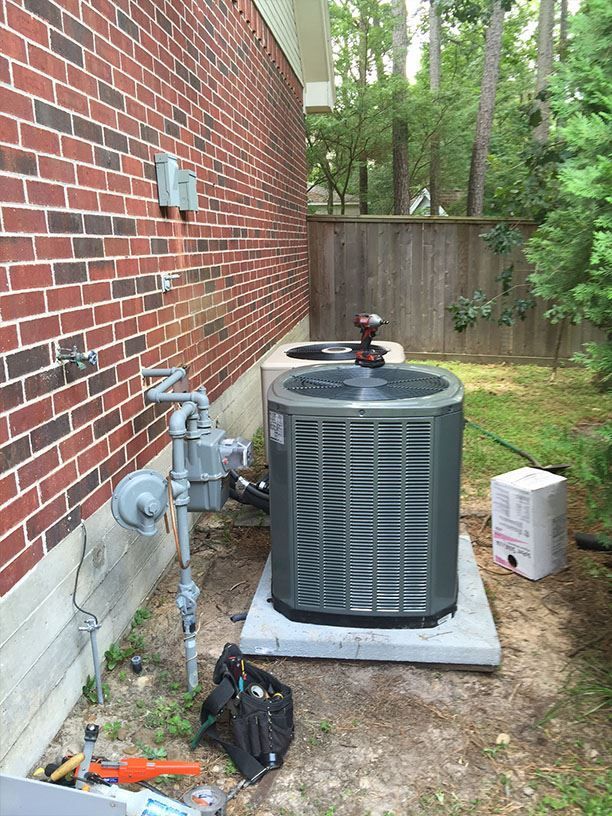 An air conditioner is sitting on the side of a brick building.