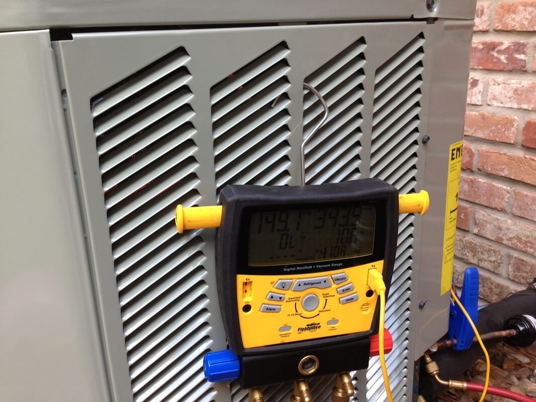 A digital thermometer is sitting on top of an air conditioner.