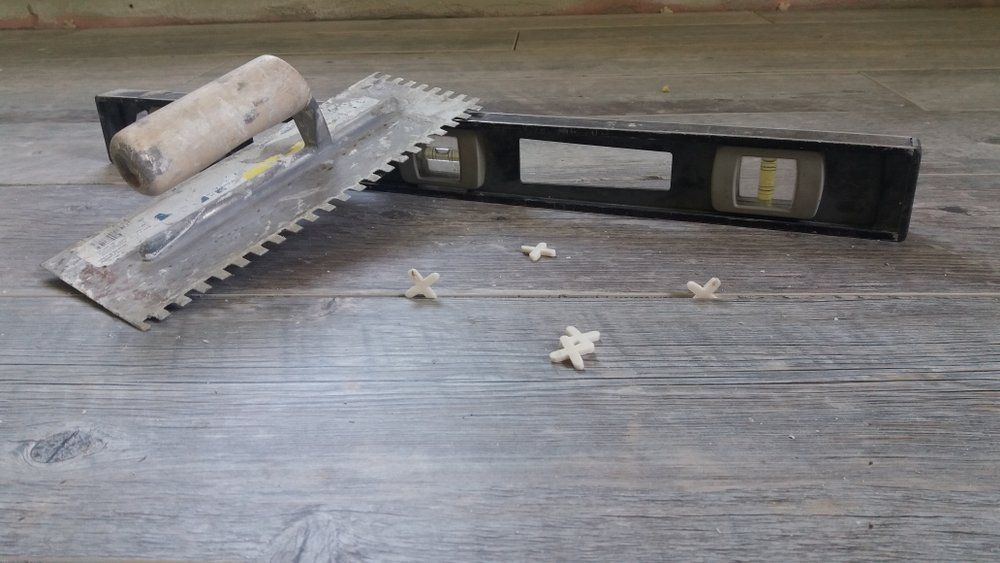 A trowel and a level are sitting on a wooden floor.