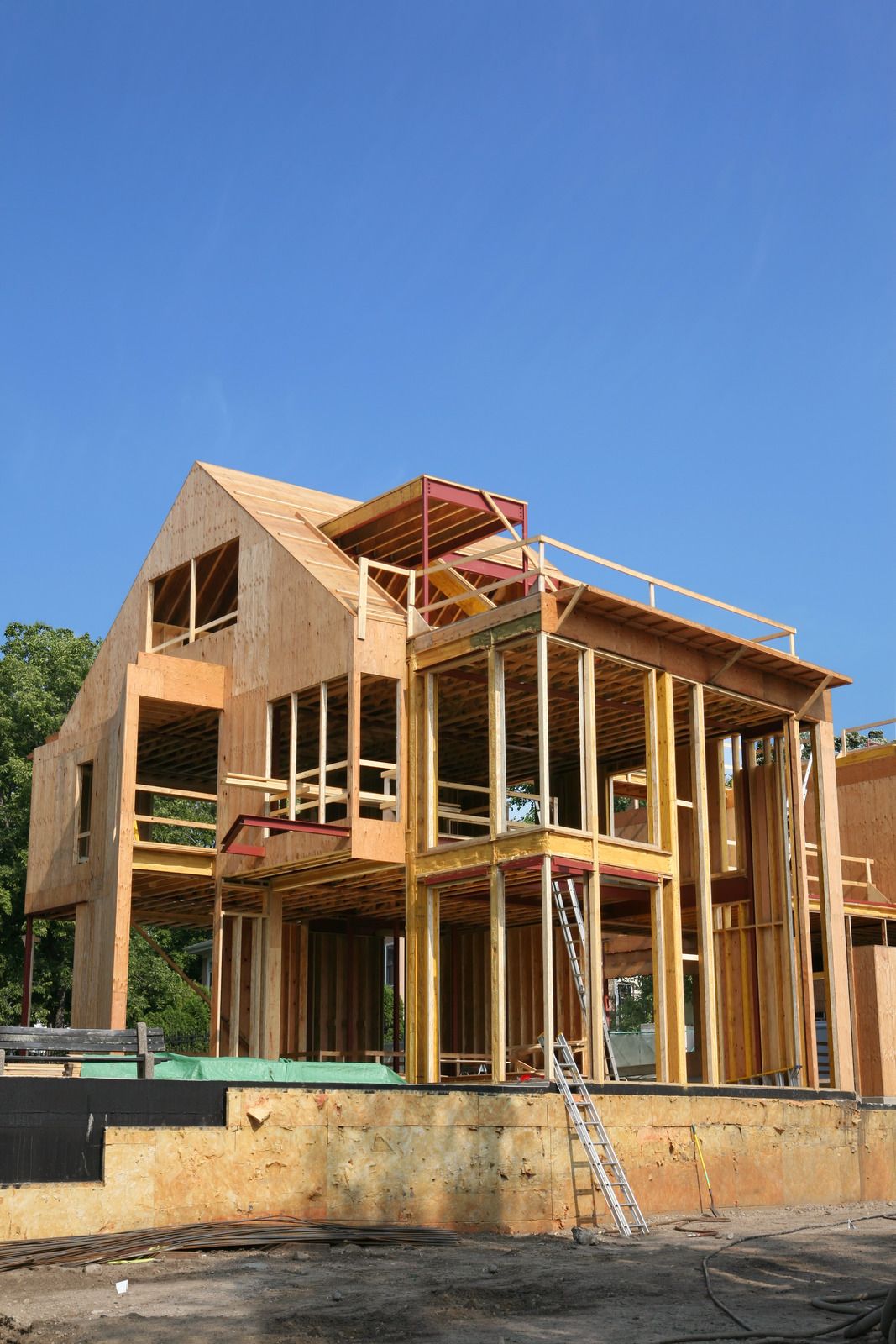 A large wooden house is being built with a blue sky in the background.