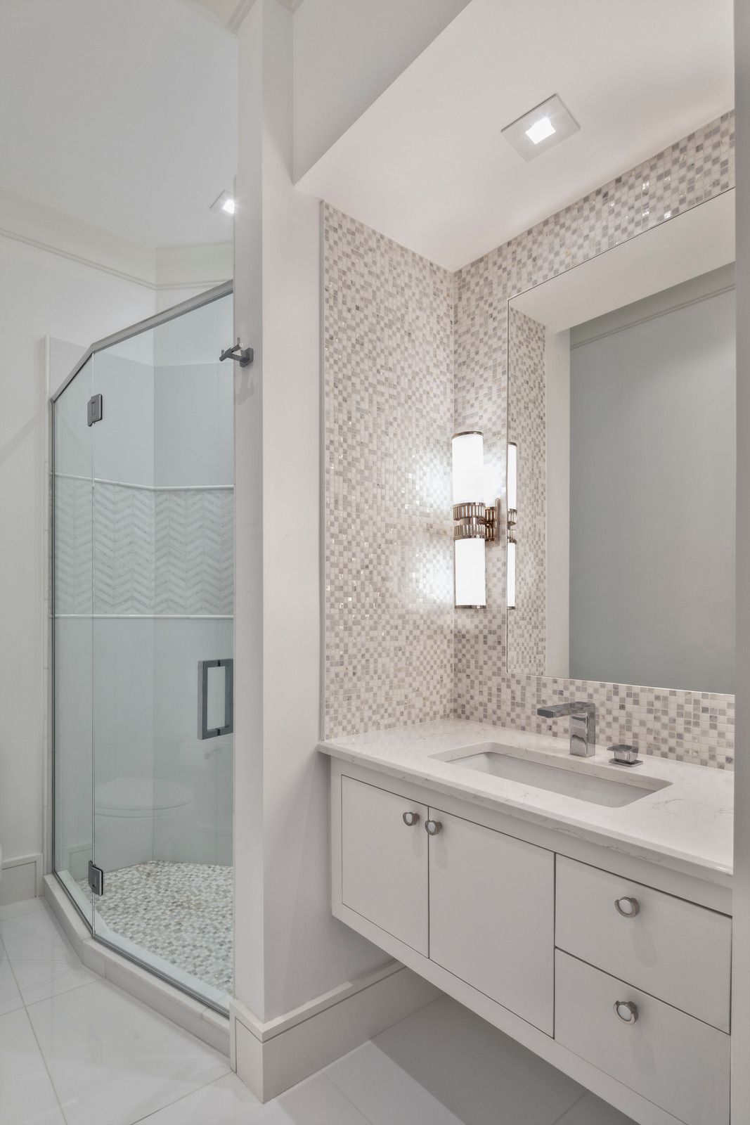 A bathroom with a sink , mirror and walk in shower.