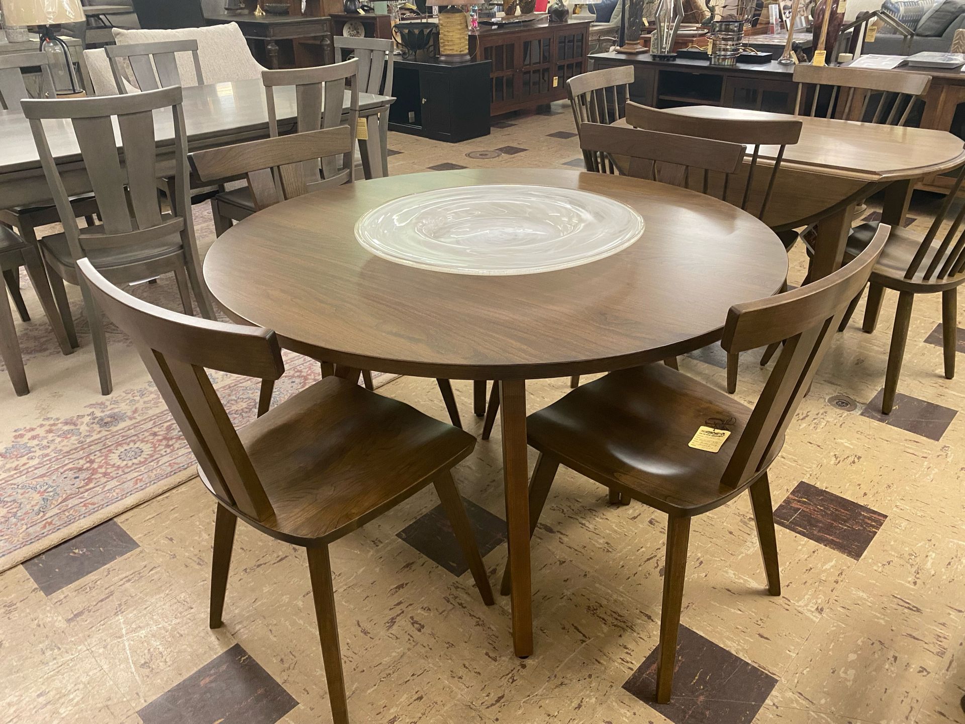 Round brown dining table with four matching chairs in a furniture store.