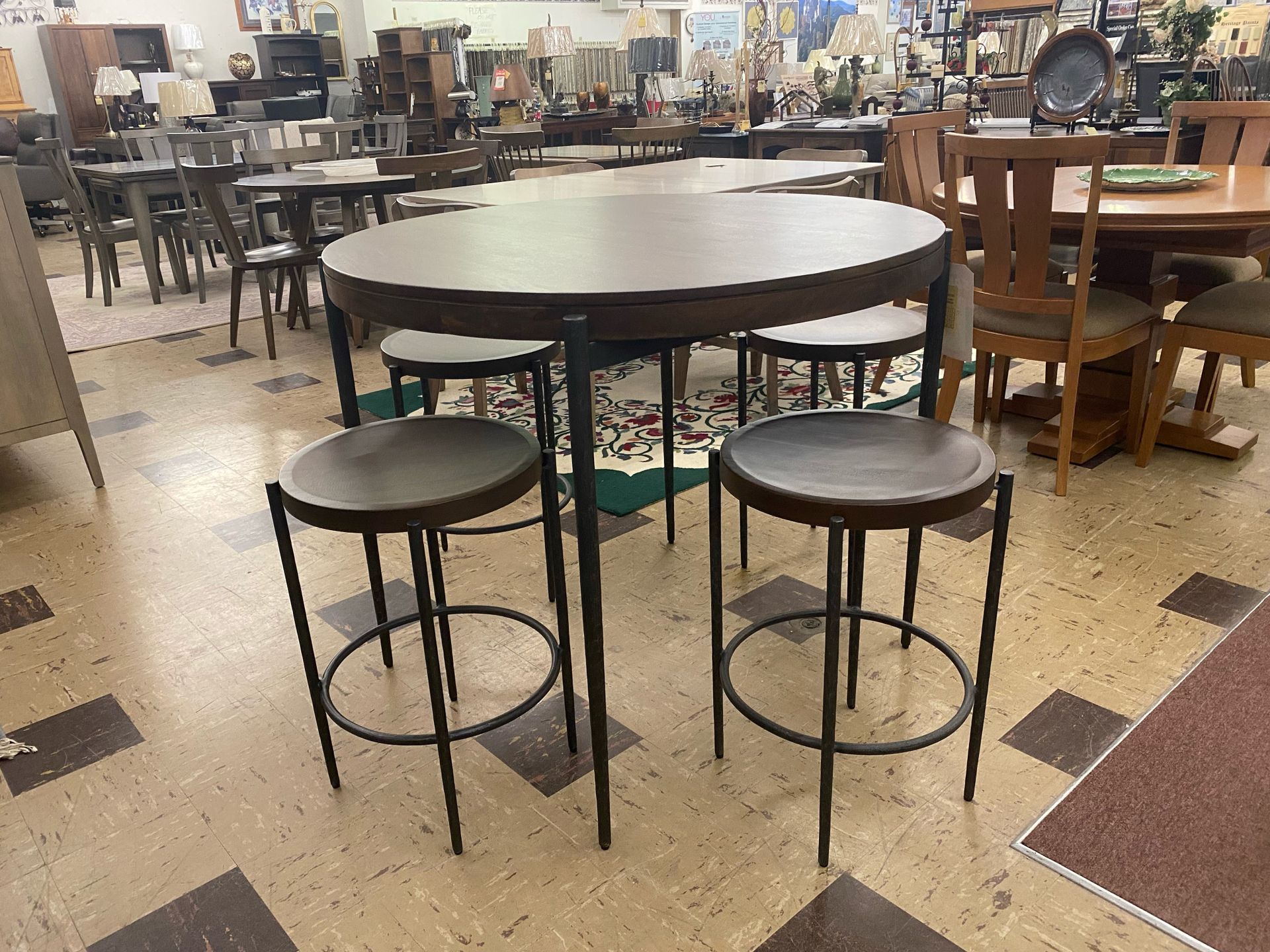 Round dark wooden table with four stools, inside furniture store.