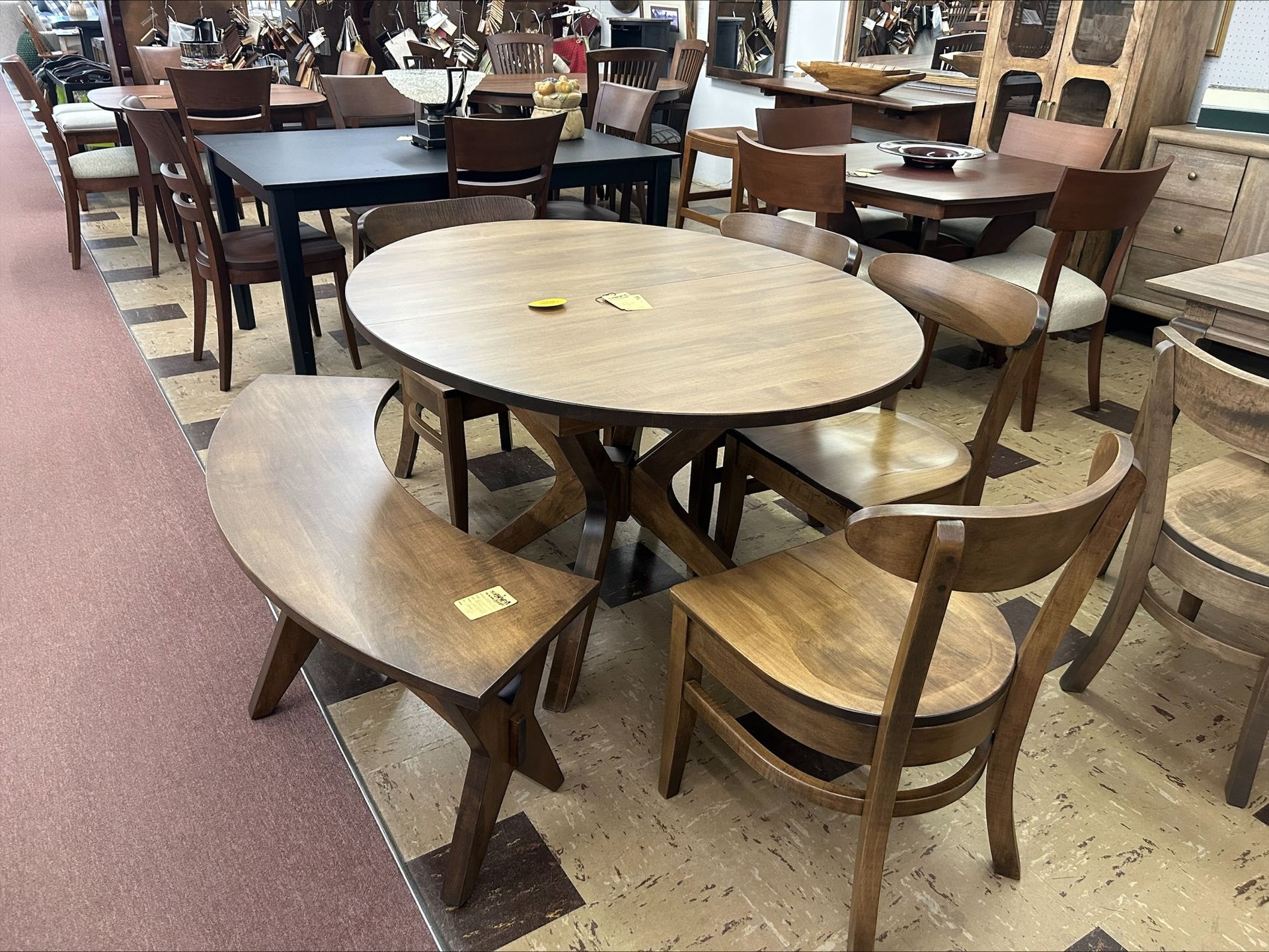 Oval dining table with six wooden chairs in a furniture store.