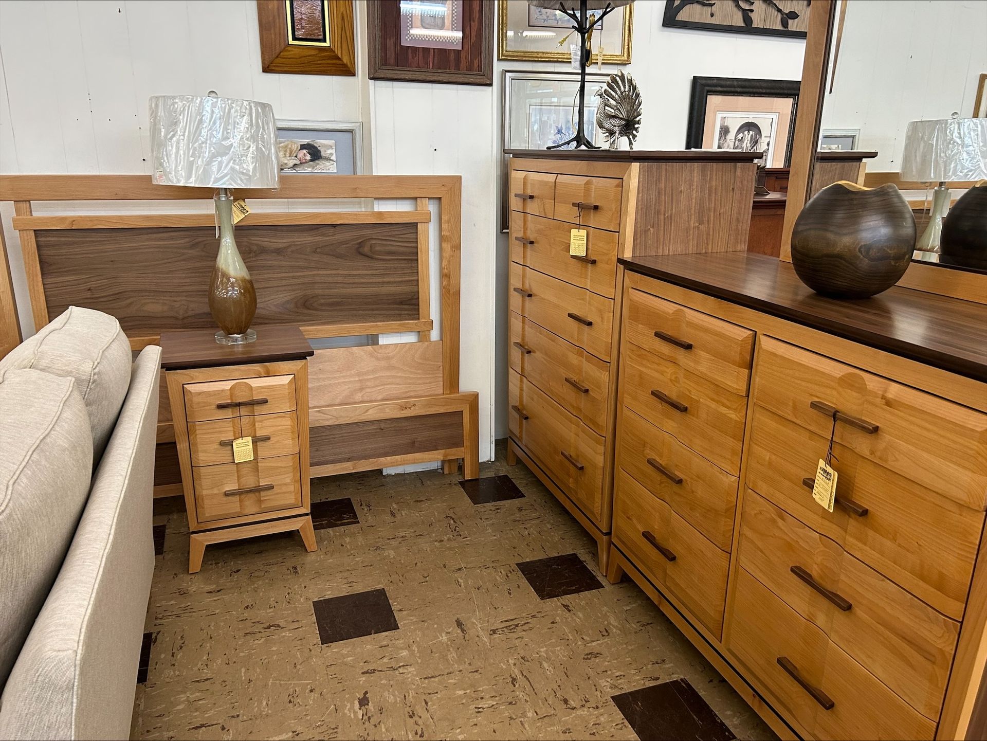 Bedroom furniture set: bed, nightstand, dresser, and mirror. Light wood with dark brown accents, beige walls.