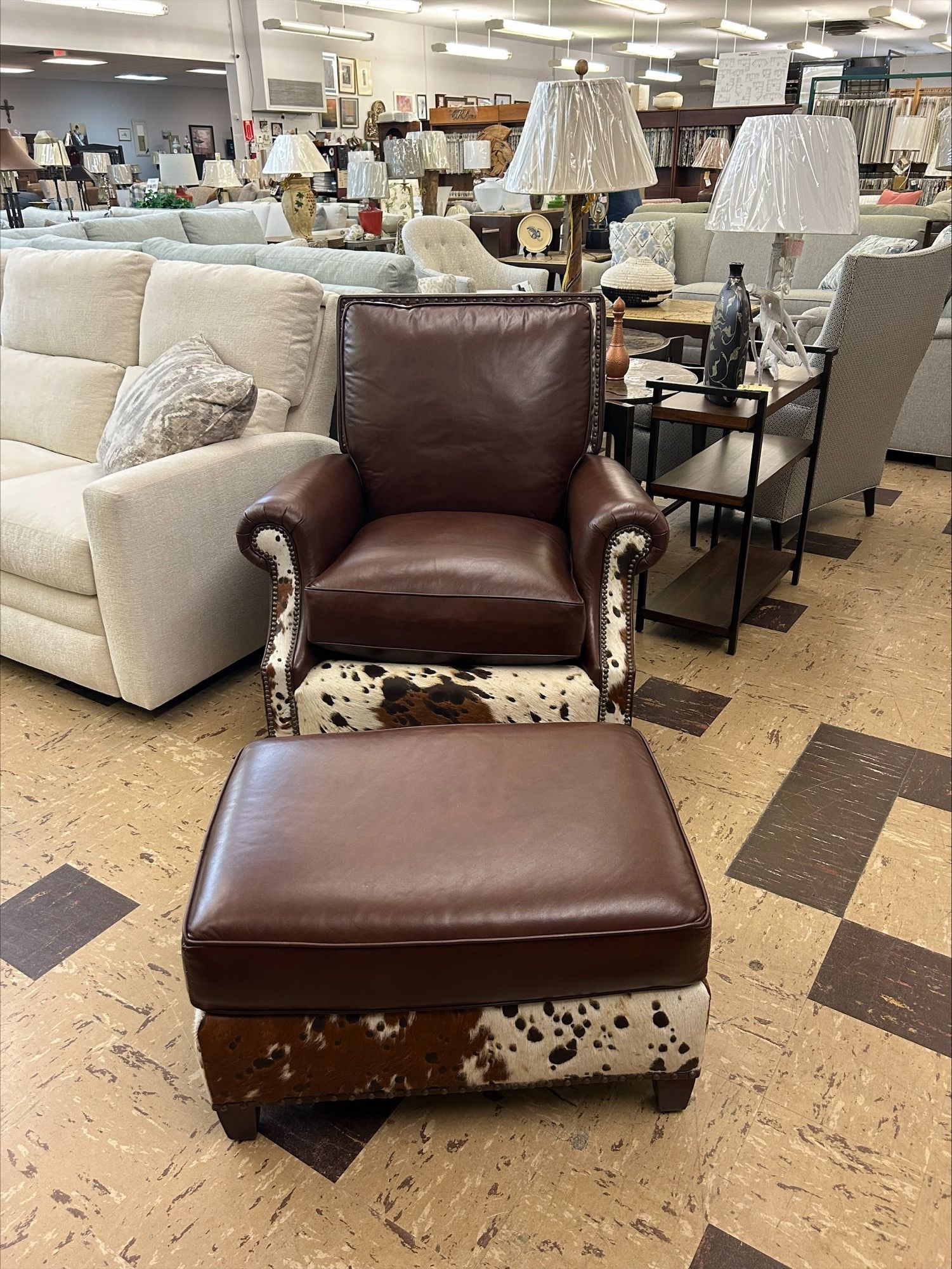 Leather armchair and ottoman on cowhide base, in furniture store.