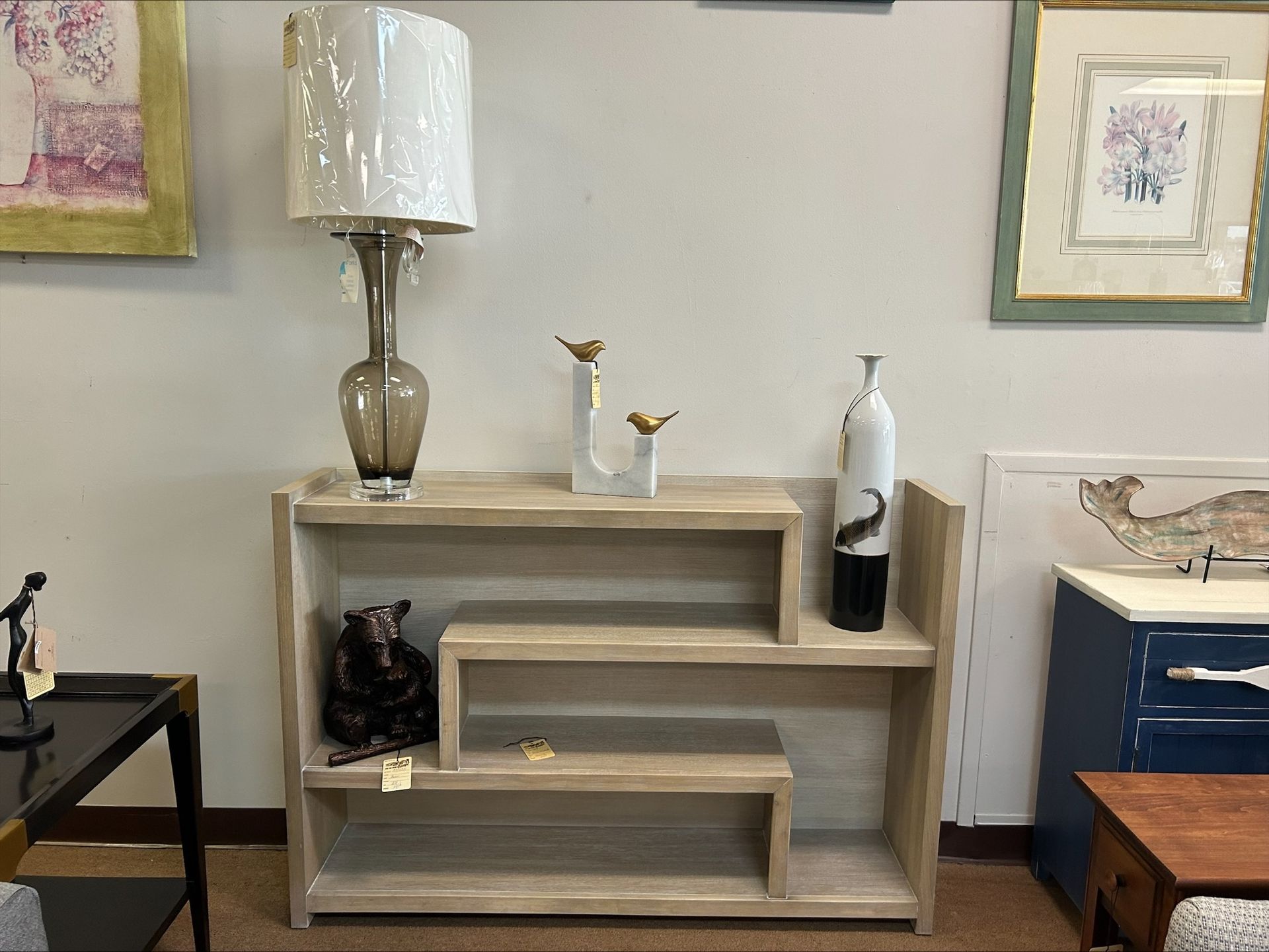 Wooden shelving unit with decorative items: lamp, vases, and bear statue.