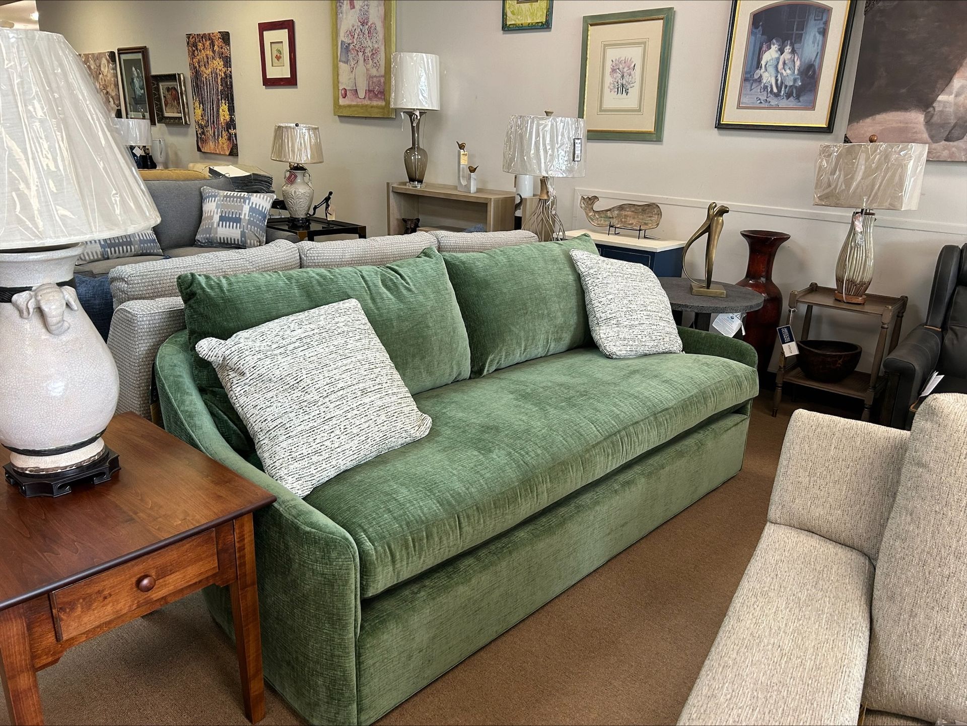 Green velvet sofa with patterned pillows in a furniture store.