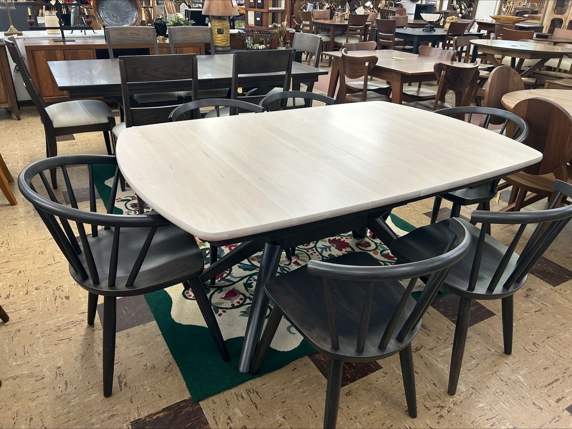 Dining table with six black armchairs in a showroom setting.