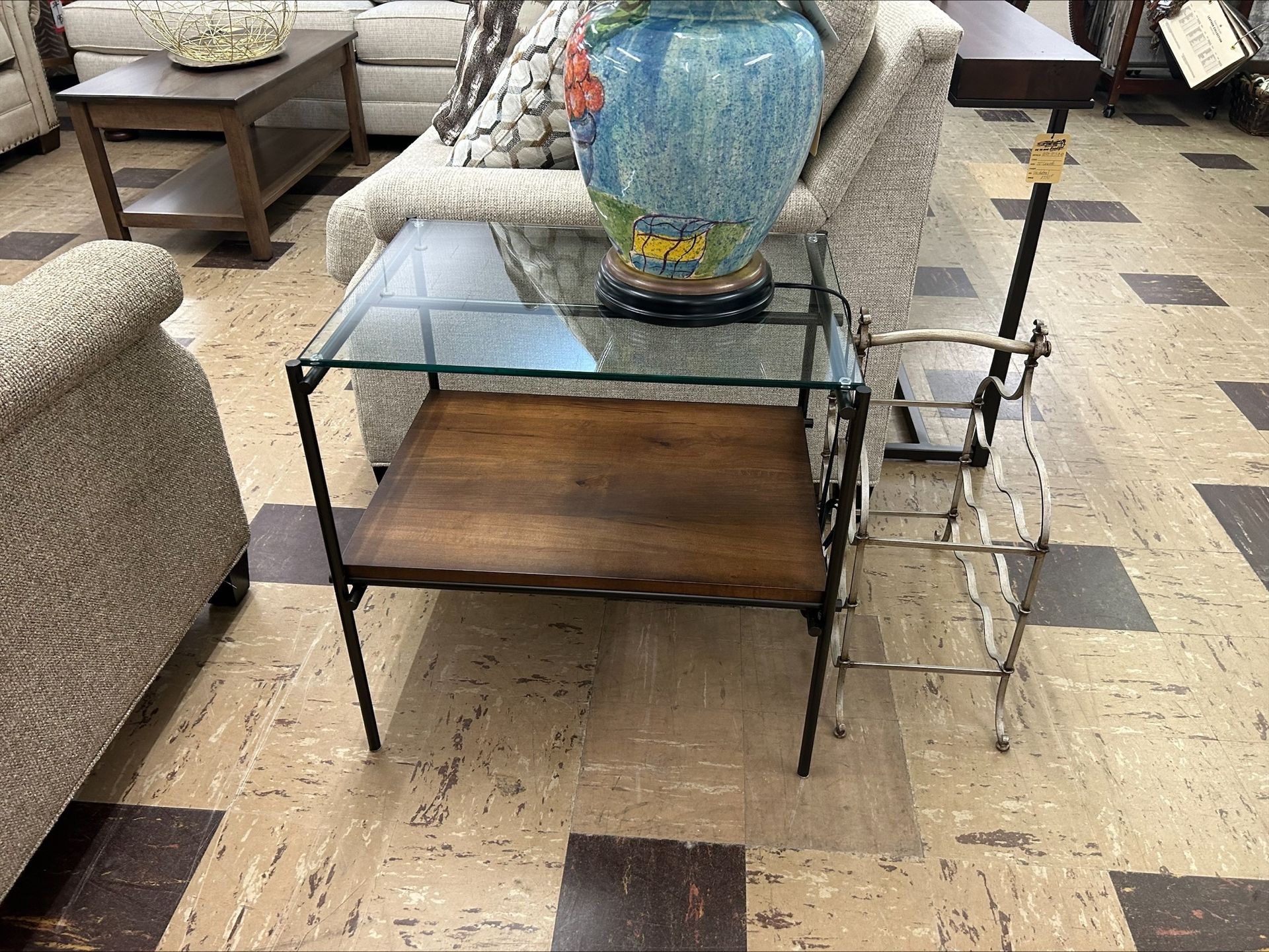 Glass and wood side table with a lamp next to it.