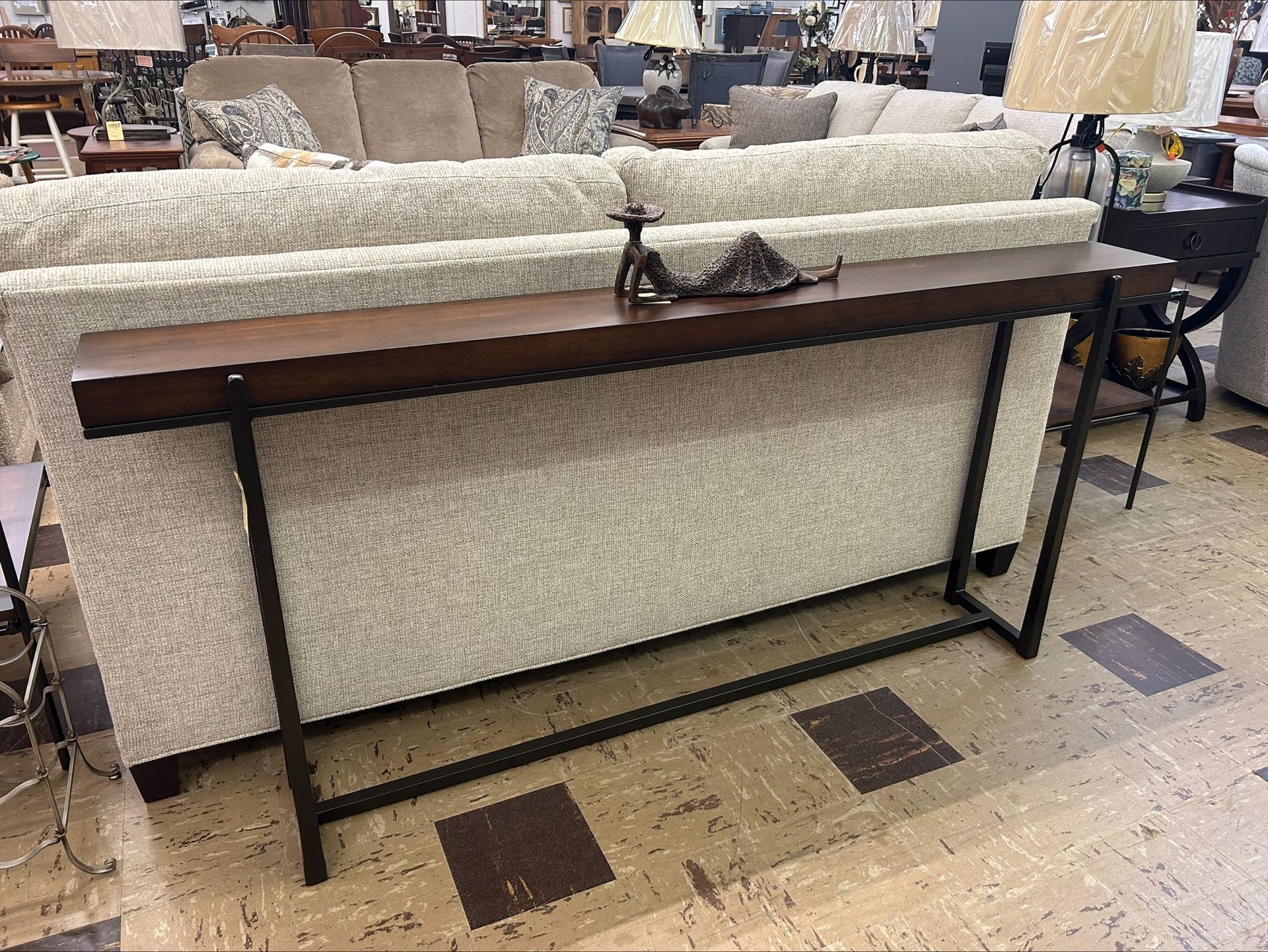 Long, brown console table behind a tan couch with black metal legs.
