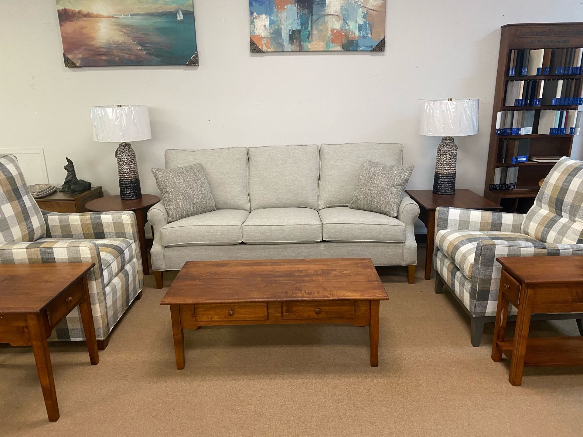 Living room furniture set: sofa, armchairs, coffee table, side tables with lamps, and a bookcase.