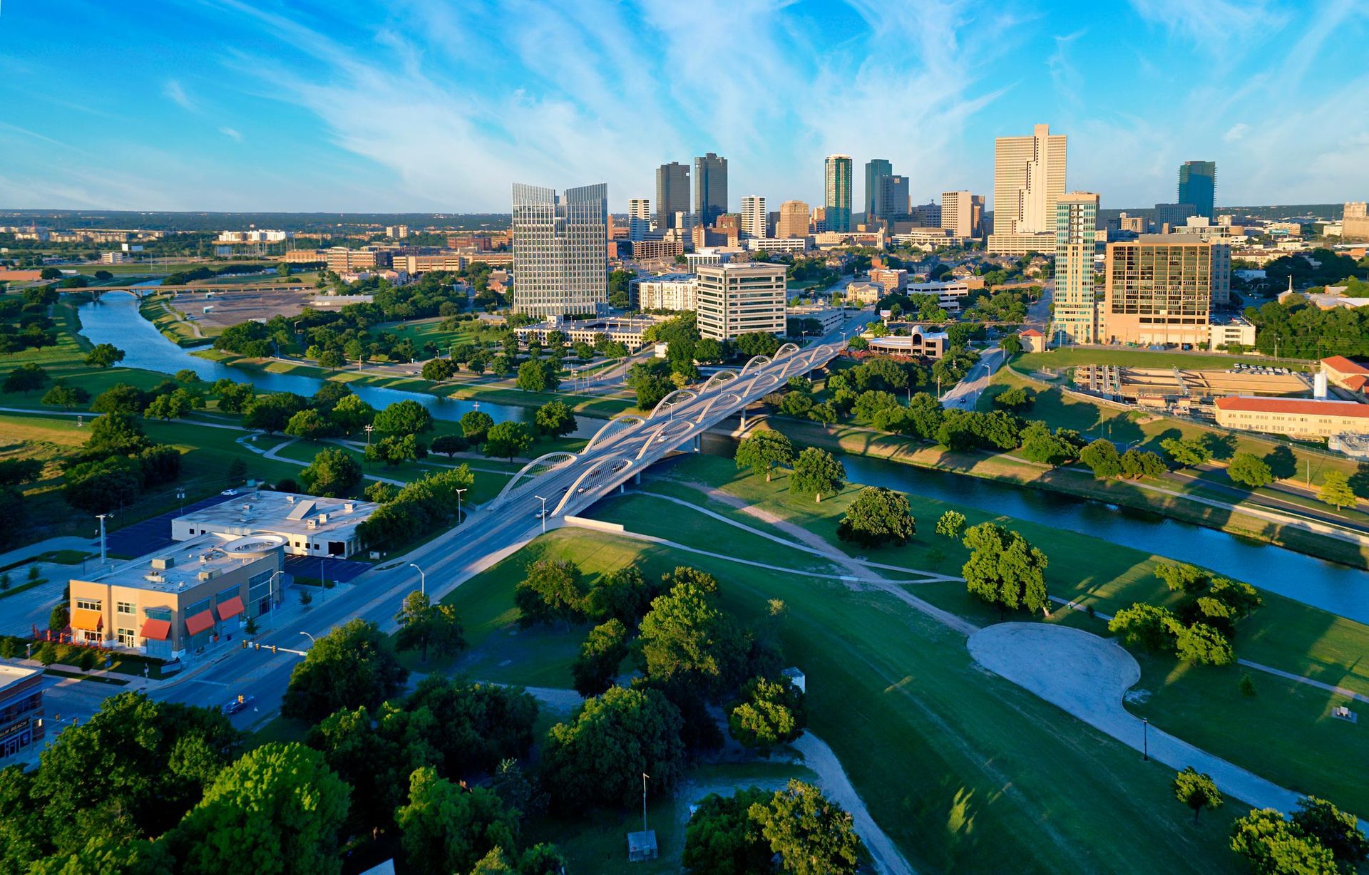 An aerial view of a city with a bridge over a river and a city skyline in the background.