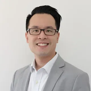 A man wearing glasses and a suit is smiling for the camera.