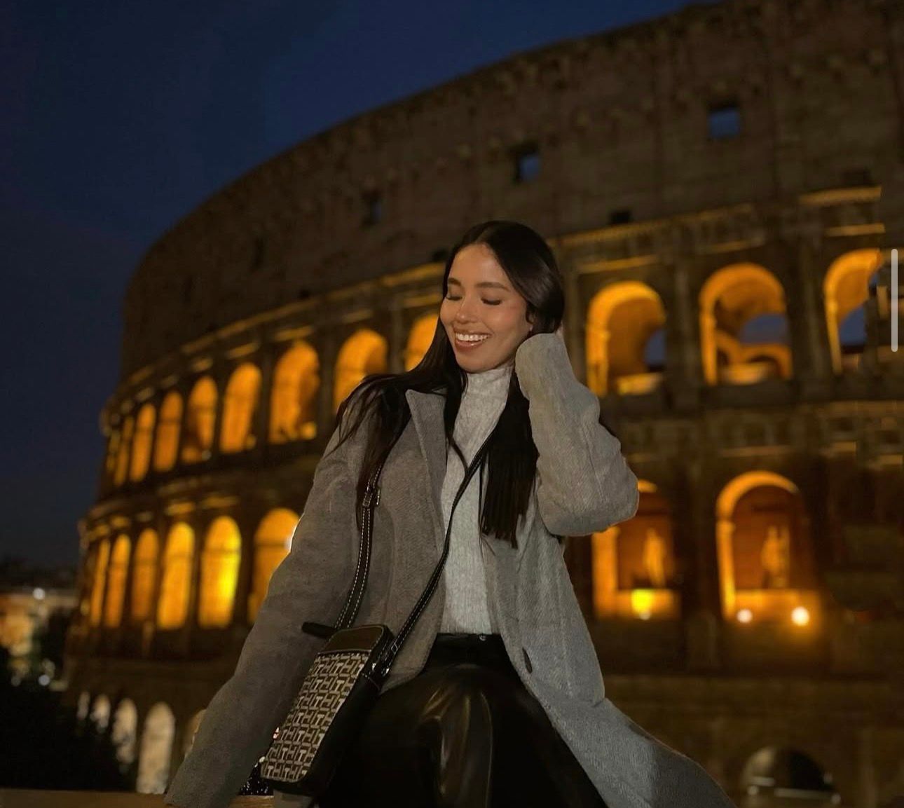 A woman is holding a cup of coffee in a park.