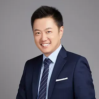 Tony in a suit and tie is smiling for the camera.