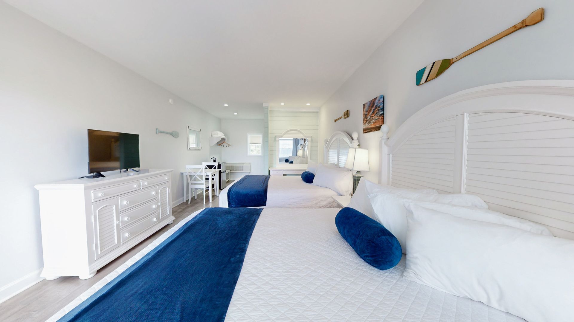 A hotel room with two beds , a dresser and a flat screen tv.