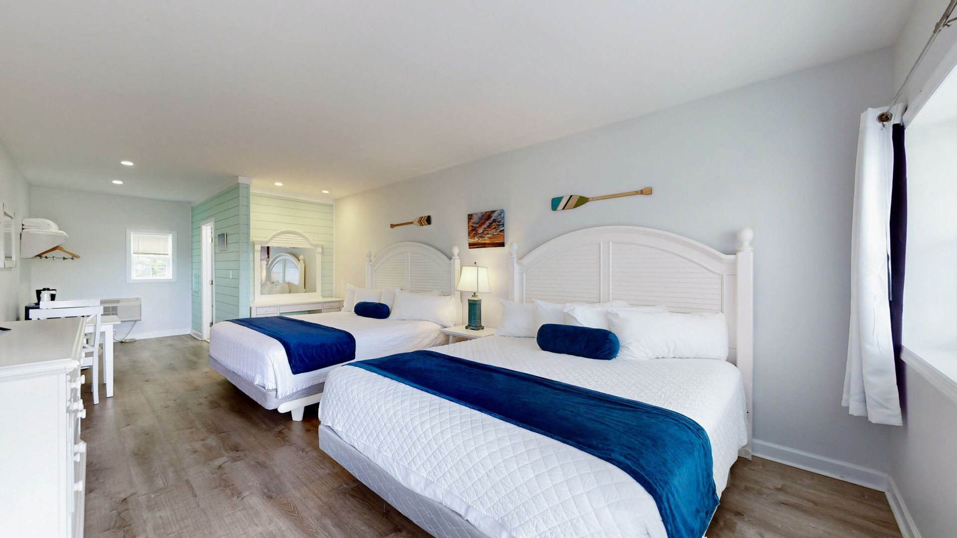 A hotel room with two beds and a dresser.