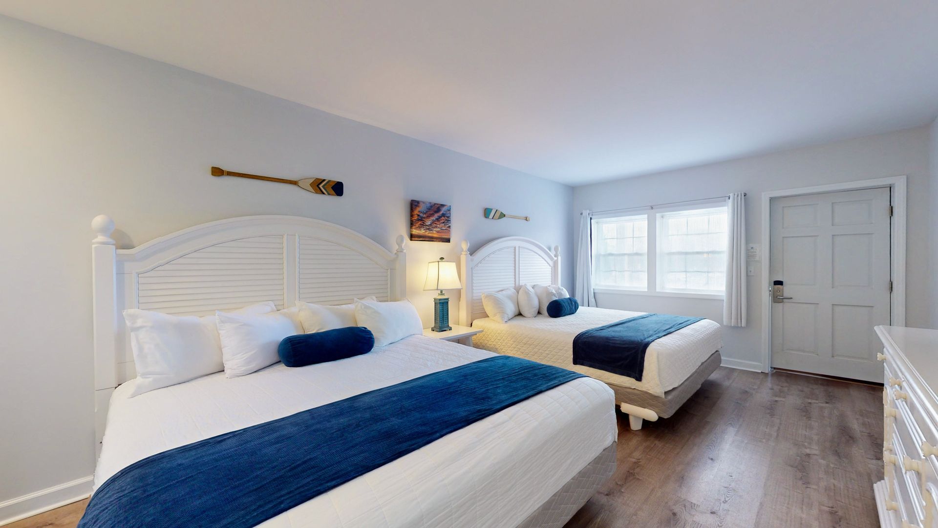 A hotel room with two beds and a dresser.
