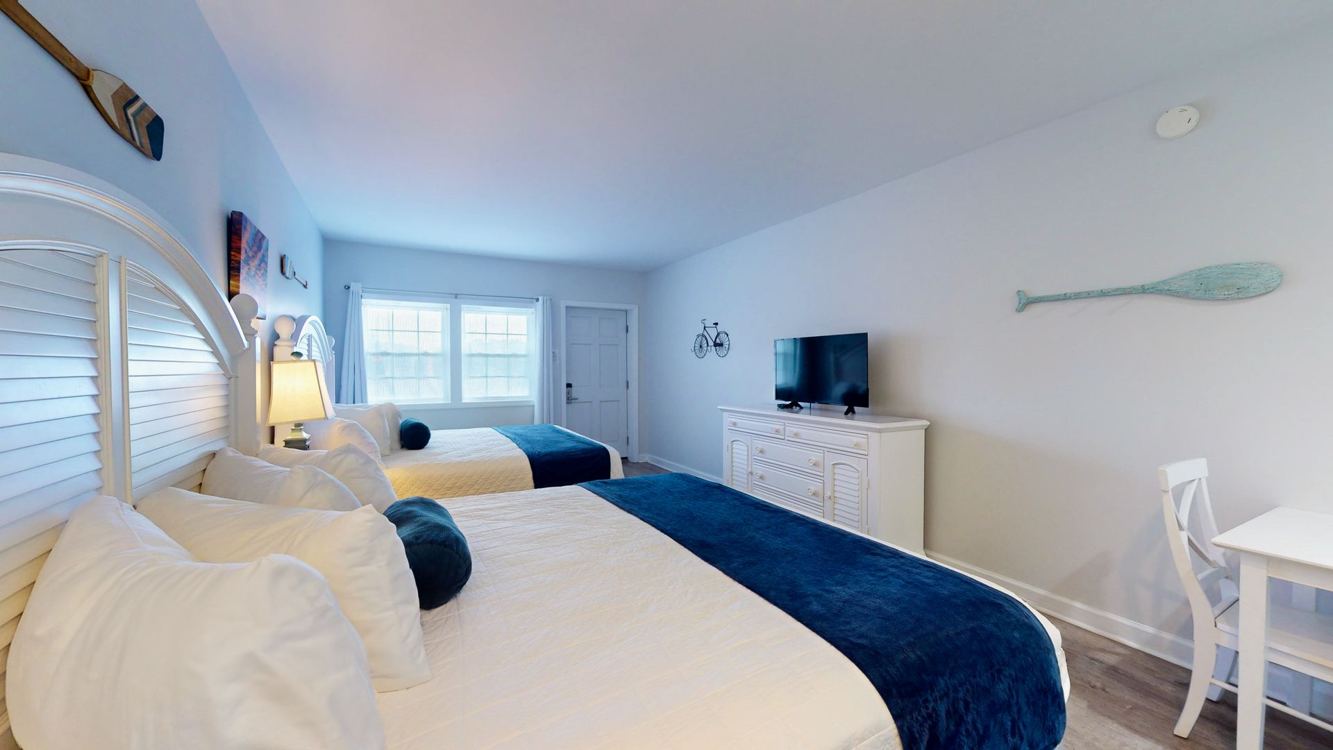 A hotel room with two beds , a desk and a television.